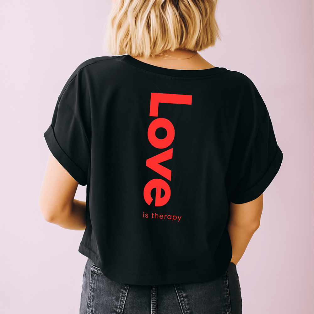 Une femme de dos porte un t-shirt noir oversize avec écrit 'Love' imprimé en rouge sur le dos.