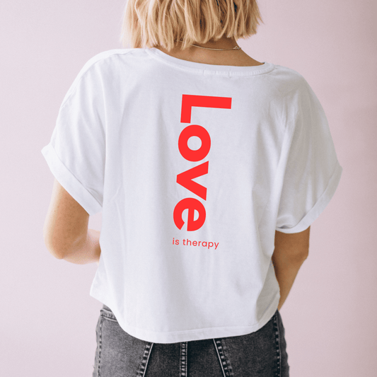 Une femme de dos porte un t-shirt blanc oversize avec écrit 'Love' imprimé en rouge sur le dos.
